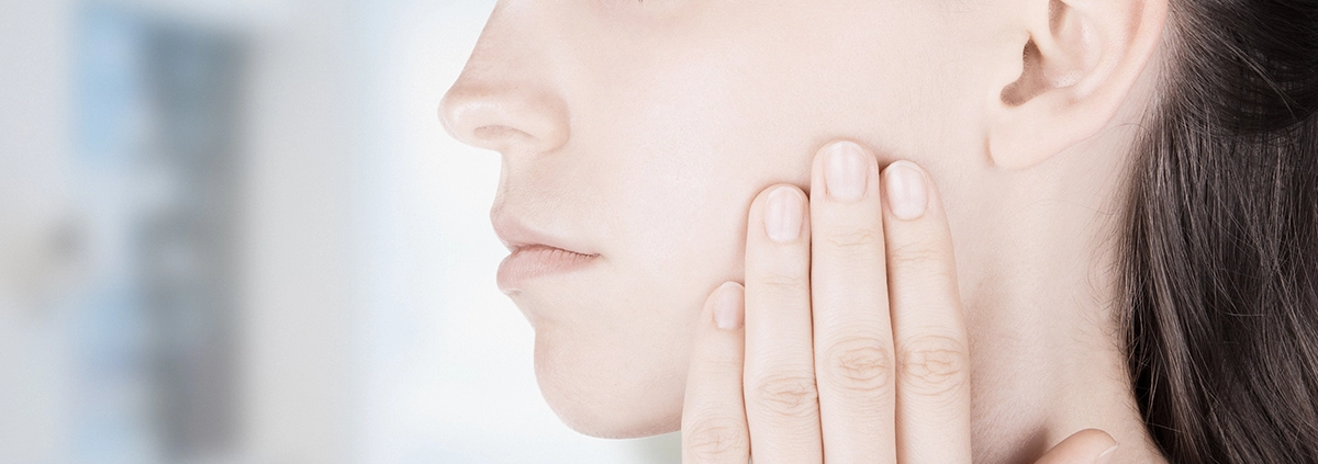 Frau berührt ihren Oberkiefer