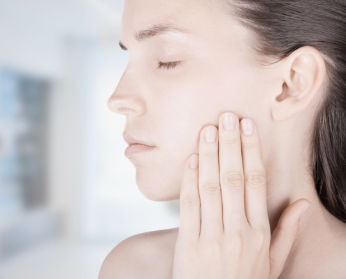 Frau berührt ihren Oberkiefer