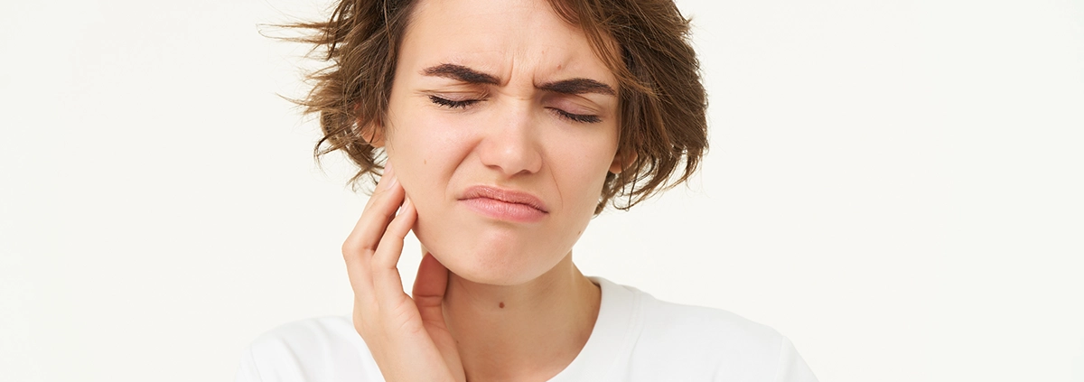 Junge Frau berührt ihr Kiefergelenk