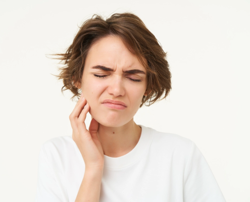 Junge Frau berührt ihr Kiefergelenk